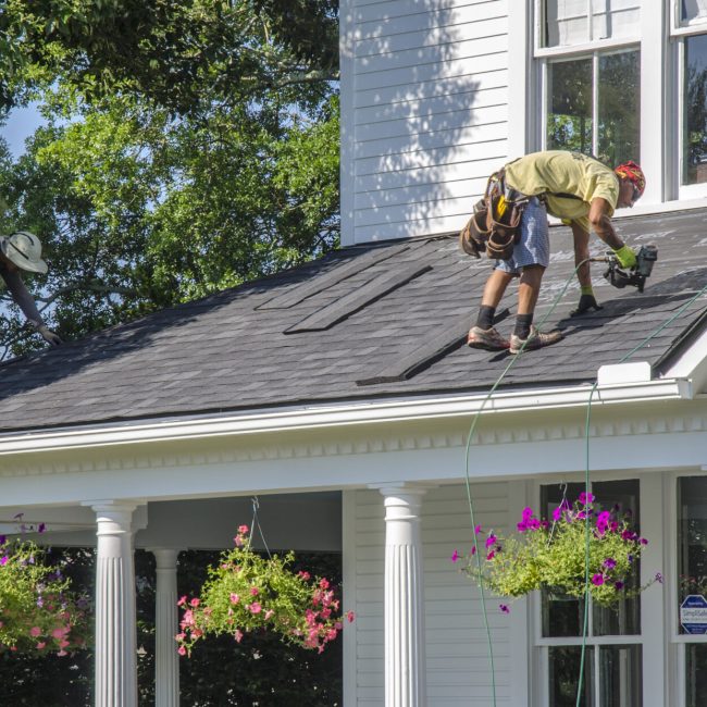 Belmont, North Carolina, USA - June 3, 2018: Roofing contractors replace roofs on residents’ homes in Belmont, North Carolina after a hail storm moved through the area on April 15, 2018. Golfball-sized hail was wide-spread and caused much property damage–especially to roofs. Roofing contractors are working seven days a week in temperatures over 90 degrees to meet demand from homeowners. Even at this rate, it could take several years to replace all of the roofs which received damage from the storm.